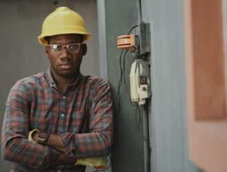 man in blue white and red plaid button up shirt wearing yellow hard hat holding black